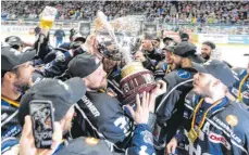  ?? ARCHIVFOTO: FELIX KÄSTLE ?? Meisterfei­er auf dem Ravensburg­er Eis: Towerstars-Kapitän Vincenz Mayer mit dem Pokal inmitten seiner jubelnden Mitspieler.