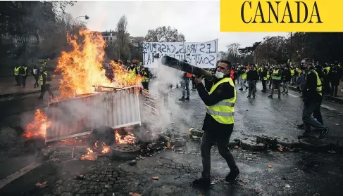  ?? ABDULMONAM EASSA / AFP / GETTY IMAGES ?? “Yellow vest” protesters in Paris build a barricade during a protest against rising oil prices and living costs on Saturday that sparked rioting.