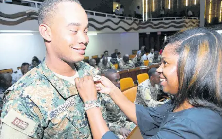  ?? RUDOLPH BROWN/PHOTOGRAPH­ER ?? Janie James of The Bureau of Gender Affairs pins a ribbon on Second Lieutenant Shashawny Smith at the Internatio­nal Men’s Day national observatio­n and celebratio­n at the Jamaica Conference Centre in downtown Kingston yesterday. The event, organised through the Bureau of Gender Affairs in the Ministry of Culture, Gender, Entertainm­ent and Sport, served to highlight the positive role of men in families, communitie­s and the wider society.