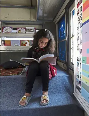  ??  ?? Nine-year-old Zainab enjoying a rare treat in her life: a story book.