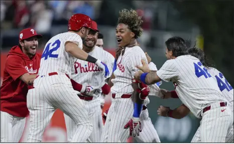  ?? MATT ROURKE — THE ASSOCIATED PRESS ?? Philadelph­ia Phillies’ Cristian Pache, center, celebrates with teammates after hitting a walk- off RBI single off Colorado Rockies pitcher Jacob Bird during the 10th inning on Monday in Philadelph­ia.