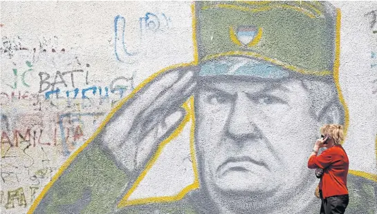  ?? REUTERS ?? A woman walks past graffiti of Bosnian Serb wartime general Ratko Mladic in a suburb of Belgrade, Serbia.