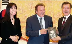  ?? Foto: Yonhap, dpa ?? Der südkoreani­sche Präsident Moon Jae in, Altkanzler Gerhard Schröder und Soyeon Kim anlässlich der Vorstellun­g einer Schröder Biografie.