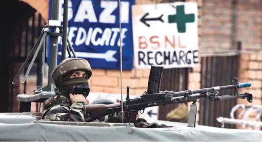  ??  ?? A soldier guards the roadside checkpoint outside Srinagar Internatio­nal Airport