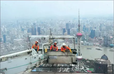  ?? YANG JIANZHENG / FOR CHINA DAILY ?? Workers prepare to clean the walls of the Shanghai World Financial Center on Jan 4, the first working day this year. Their platform often rests 500 meters above the ground.