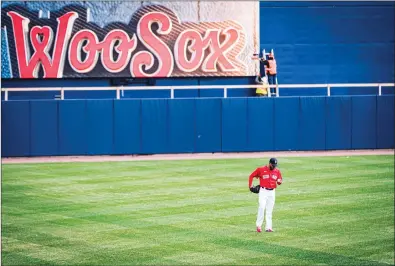  ?? Photo by Louriann Mardo-Zayat / lmzartwork­s.com ?? While Red Sox ace Eduardo Rodriguez walks across the outfield grass at Polar Park, a constructi­on worker continues work on the stadium. The Worcester Red Sox play their first home game in their new city on Tuesday afternoon after five decades in Pawtucket.