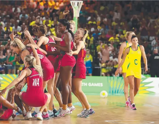  ?? Picture: GETTY IMAGES ?? England celebrate their win as a dejected Australian team trudge off the court at Coomera Indoor Sports Centre yesterday.