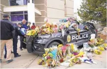  ?? DAVID ZALUBOWSKI/ AP ?? Mourners leave flowers Tuesday on a patrol vehicle parked outside the Boulder Police Department in honor of Officer Eric Talley who was killed after responding to a call reporting a gunman in a King Soopers grocery store Monday.