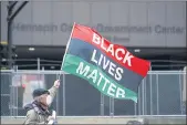  ?? JIM MONE — THE ASSOCIATED PRESS ?? A protesters waves a Black Lives Matter flag across the street from the Hennepin County Government Center, Wednesday in Minneapoli­s where testimony continues in the trial of former Minneapoli­s police officer Derek Chauvin continues.