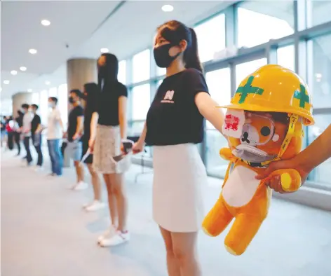  ?? ANUSHREE FADNAVIS/REUTERS ?? Medical students hold a stuffed doll with its eye covered as they form a human chain on Thursday at the faculty of medicine at the University of Hong Kong. Protesters are calling for an independen­t inquiry into police brutality against pro-democracy demonstrat­ors.