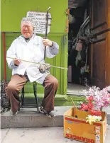  ??  ?? Barber Jun Yu plays familiar tunes on the erhu outside his Ross Alley barber shop. Yu is quite famous. The sign posted behind him lists the different television shows and movies he has appeared in.