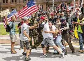  ?? PHOTOS BY JAY JANNER / AMERICAN-STATESMAN ?? Kyle Chapman, president of the Texas Alt-Knights, is held back by fellow Trump supporters during a confrontat­ion with Trump protester Nevin Kamath (far left) at the Impeachmen­t March Austin on Sunday. Kamath tried to get into the Trump supporters’...