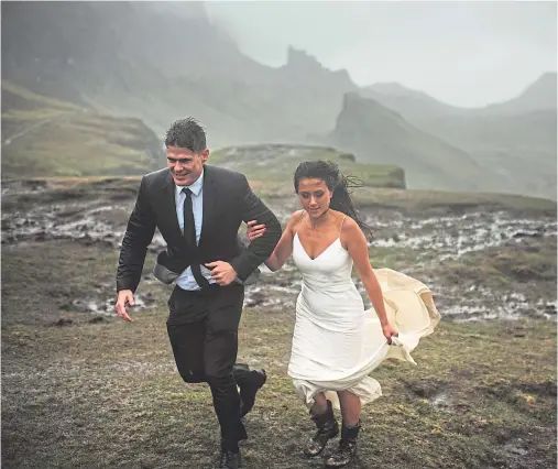  ??  ?? STUNNING IMAGE: A muddy and windswept James and Lisa Mortier on Skye pose for their wedding photograph­s with a difference