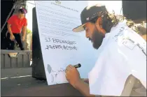  ?? PHOTOS BY KARL MONDON – STAFF PHOTOGRAPH­ER ?? Juan Carlos Araujo, founder of local arts group Empire 7 Studios, signs a protest letter about the gray-washing of the Mural de la Raza in East San Jose during a rally on Mexican Independen­ce Day, Sunday.