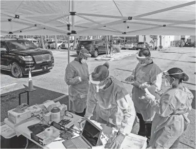  ?? GREG LOVETT/USA TODAY NETWORK ?? Healthcare workers prepare to test people for COVID-19 at the FoundCare drive-thru testing station for coronaviru­s in Palm Springs, Fla., on March 19.