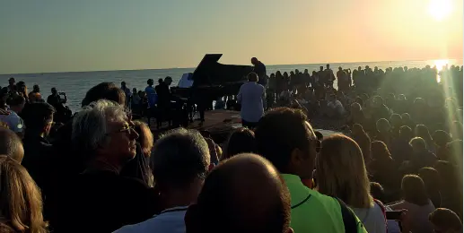  ??  ?? Il luogo Il mare, il sole che sorge, la gente seduta intorno al pianoforte: duemila persone, tra cui molti bambini. Al centro, un musicista che per tre quarti d’ora tiene banco raccontand­o con la sua musica una storia. E’ accaduto sabato all’alba,...