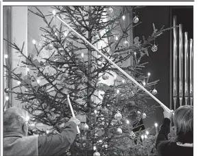  ?? Rick Steves’ Europe/CAMERON HEWITT ?? In Switzerlan­d, some families still use real candles to adorn their Christmas tree.