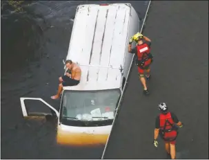  ?? The Associated Press ?? VAN RESCUE: U.S. Coast Guard rescue swimmer Samuel Knoeppel, center, and Randy Haba, bottom right, approach to Willie Schubert of Pollocksvi­lle, N.C., on a stranded van in Pollocksvi­lle on Monday in the aftermath of Hurricane Florence.