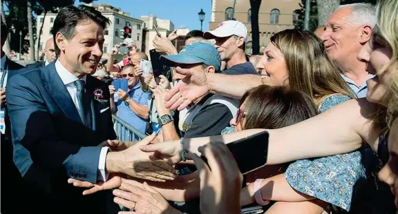  ??  ?? I saluti Il presidente del Consiglio Giuseppe Conte, 53 anni, all’altare della Patria stringe le mani alla folla che gli augura buon lavoro per il suo nuovo incarico