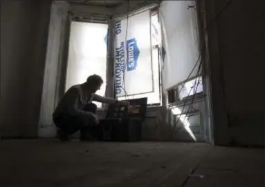  ?? AP FILE PHOTO ?? Artist Adam Frelin adjusts a timer for window lights for the Breathing Lights art project in a vacant house in Troy in this Nov. 1, 2016, photo. The two-month, three-city public art project led to creation of the Green & Healthy Homes Initiative, which...