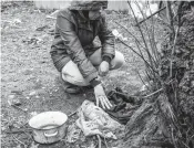  ?? ?? Iryna Abramova kneels to touch the clothing her husband was wearing before Russian soldiers destroyed their home, marched them outside at gunpoint and executed him.