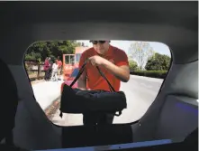  ??  ?? Zume delivery driver Gustavo Vega loads a pizza into his car along El Camino Real in Palo Alto.