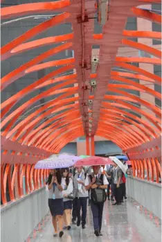  ?? Chris Navarro ?? Students use their umbrellas to stay dry as they cross a roofless pedestrian overpass after tropical depression ‘Maring’brought heavy rains in towns and cities in Pampanga yesterday. -