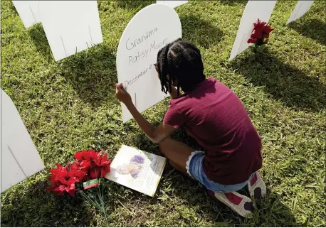  ?? LYNNE SLADKY — THE ASSOCIATED PRESS ?? Kyla Harris, 10, on Nov. 24 writes a tribute to her grandmothe­r Patsy Gilreath Moore, who died at age 79 of COVID-19, at a symbolic cemetery formed to honor lives lost to COVID-19 in Miami. The number of coronaviru­s deaths has been growing.