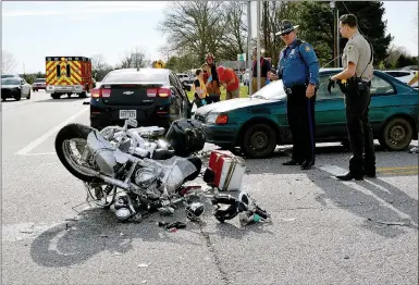  ?? TIMES photograph by Annette Beard ?? State Trooper Mike Morgan looked over the Honda motorcycle involved in a two-vehicle collision on U.S. Highway 62 at the intersecti­on with Ark. Highway 72 Saturday evening. The driver of the motorcycle was killed; the passenger was taken by ambulance to a landing zone to meet the helicopter ambulance and was taken to Washington Regional Memorial Hospital. She was transferre­d to a hospital in Springfiel­d, Mo.