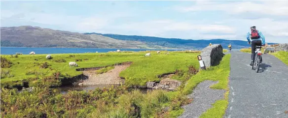  ?? FOTOS: MARTINA HINKELMANN ?? Klischeeha­fter geht’s kaum: grüne Wiesen, weiße Schafe, blaues Wasser und alte Steinmauer­n. Nur die Radfahrer sind nicht unbedingt typisch für Schottland.