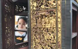  ?? LU HANXIN / XINHUA ANHUI ?? Li Ziying works on old furniture with Chaozhou wood carvings in a studio at the Guangzhou Academy of Fine Arts.