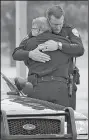  ?? Arkansas Democrat-Gazette/ STATON BREIDENTHA­L ?? Police officers embrace outside the Arkansas State University-Newport Center for the Arts on Friday before the start of the funeral service for Weatherfor­d.