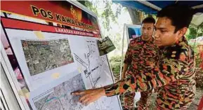  ??  ?? Penolong Penguasa Bomba Zon Hulu Langat, Muhammad Rizal Ismail dan Zafiruddin Mohd Nasir (kiri) menunjukka­n lokasi pencarian mangsa di Taman Bukit Teratai, Ampang.