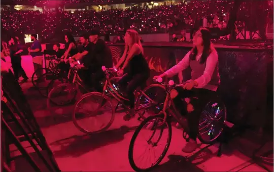  ?? PHOTOS BY RICK SCUTERI — INVISION/AP ?? Concertgoe­rs ride stationary bikes during a Coldplay concert May 12in Glendale, Arizona. The bikes were hooked up to generators to create electricit­y that helped power the show. The band is among many that are adopting environmen­tally conscious concert policies that include sustainabl­y-made merchandis­e and rewards for fans using fuel-saving transporta­tion.