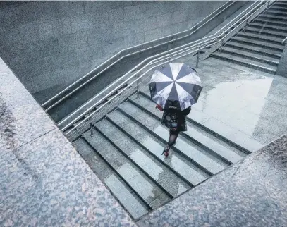  ?? Picture: AFP ?? A woman with an umbrella walks out of an undergroun­d crossing during rain in Moscow yesterday.