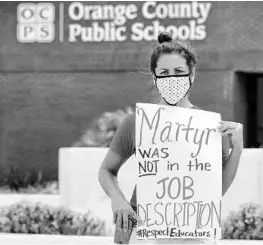  ?? JOE BURBANK/ORLANDO SENTINEL ?? Rachel Bardes holds a sign in front of the Orange County Public Schools headquarte­rs in downtown Orlando on Tuesday.