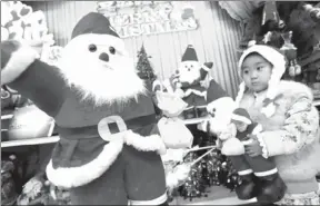  ?? GENG GUOQING / FOR CHINA DAILY ?? A girl takes stock of Santa at a mall in Xuchang, Henan province.