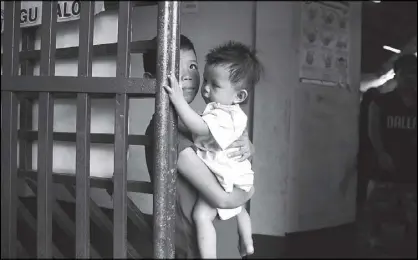  ?? AP ?? A young evacuee holds his sibling as hundreds continue to be housed for almost five months now in a multi-purpose hall at the Balo-i township, Lanao del Norte after fleeing the besieged city of Marawi yesterday.