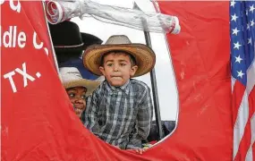  ?? Steve Gonzales / Houston Chronicle ?? From left, Jerry Henry Jr., 8, and David Melchor, 4, watch from a covered wagon as the Northeaste­rn Trail Riders make a stop Friday at B.C. Elmore Middle School.