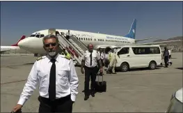  ?? WALI SABAWOON — THE ASSOCIATED PRESS ?? Pilots of Ariana Afghan Airlines walk on the tarmac after landing at Hamid Karzai Internatio­nal Airport in Kabul, Afghanista­n, on Sunday.