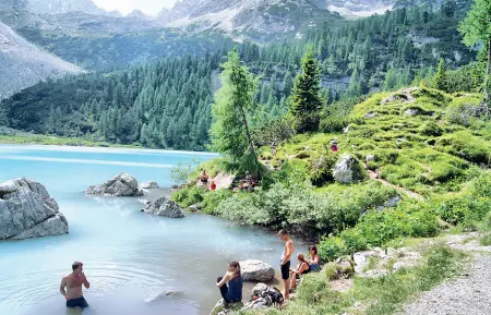  ??  ?? Come spiaggia in Alcuni turisti prendono il sole lungo le rive e si tuffano nel lago di Sorapis , uno dei laghi più belli delle Dolomiti