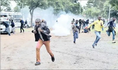  ?? PICTURE: OUPA MOKOENA ?? SEEKING COVER: Local residents flee in Marabastad, Pretoria, as police fire stun grenades during a protest against foreign nationals.