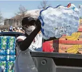  ?? Brett Coomer / Staff photograph­er ?? Eunice Russ loads a case of water Tuesday during a food distributi­on event at NRG Stadium.