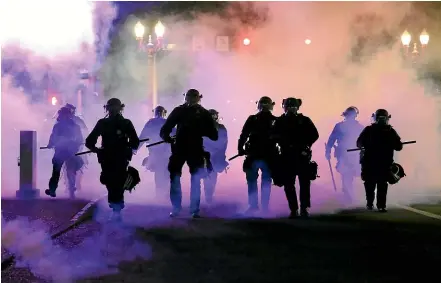  ?? AP ?? Tear gas surrounds police in Portland, Oregon, yesterday, a scene echoed across the US as protests at the death of George Floyd turned violent.