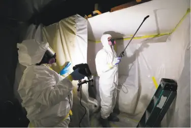  ?? Paul Sancya / Associated Press ?? Workers spray a home during asbestos abatement in Howell, Mich. Asbestos fibers can become lethal after a fire or during remodeling, lodging in lungs and causing mesothelio­ma, a form of cancer.