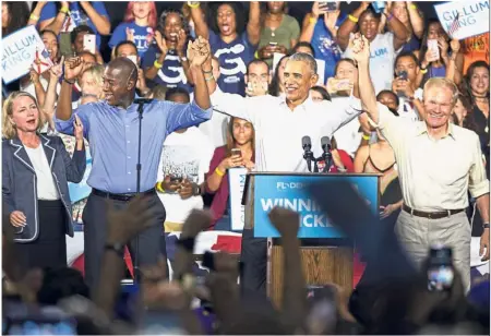  ?? — Bloomberg ?? On the campaign trail again: Obama flanked by Gillum (left) and Nelson raising their arms during a campaign rally for Florida’s Democratic candidates in Miami, Florida.