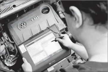  ?? Julian Stratensch­ulte
European Pressphoto Agency ?? A TECHNICIAN holds a readout device in front of a diesel engine affected by the emissions scandal in Germany. Regulators say the vehicles they tested emitted 10 to 40 times the permissibl­e nitrogen oxide level.