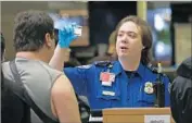  ?? Elaine Thompson Associated Press ?? A TSA OFFICER checks a passenger’s ID in April at a security checkpoint at Seattle-Tacoma airport.