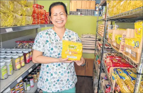  ?? ERIC MCCARTHY/JOURNAL PIONEER ?? Besides ingredient­s for making meals, Ruby Gadbilao demonstrat­es her Bloomfield store also carries ready-to-eat snacks, like cheesecake­s.
