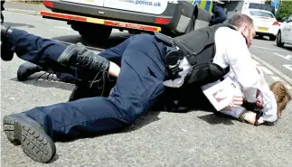  ??  ?? Arrest: Police pin a suspect to the ground after a photograph­er was punched